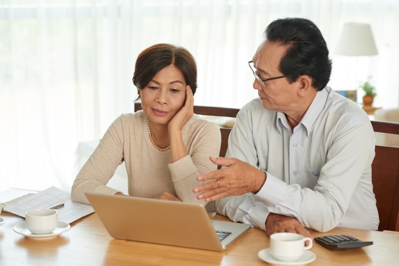 Unhappy Vietnamese senior couple discussing family budget