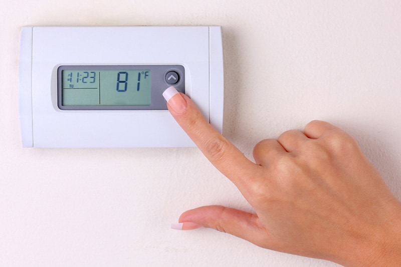 Blog Title: How to Set Your Programmable Thermostat Photo: someone setting a thermostat